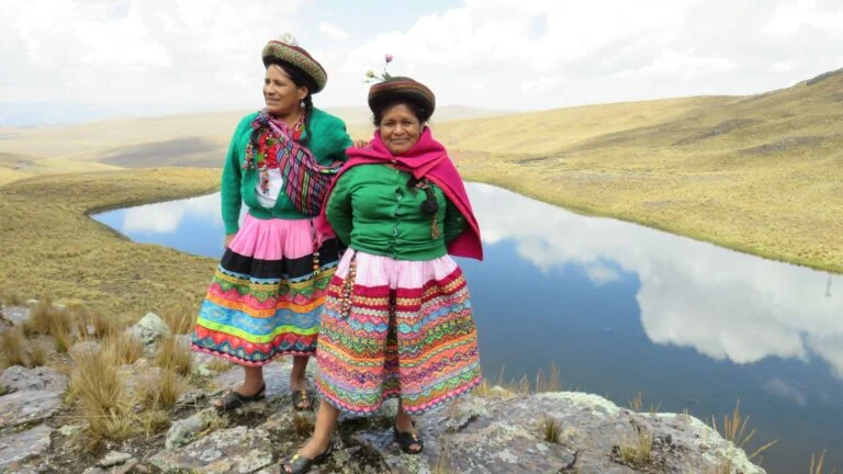 Zwei Frauen stehen vor Teich mit traditioneller Bekleidung