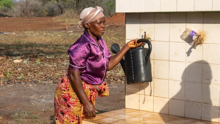Eine Frau in einem Dorf in Mosambik holt Wasser an einer Brunnenanlage