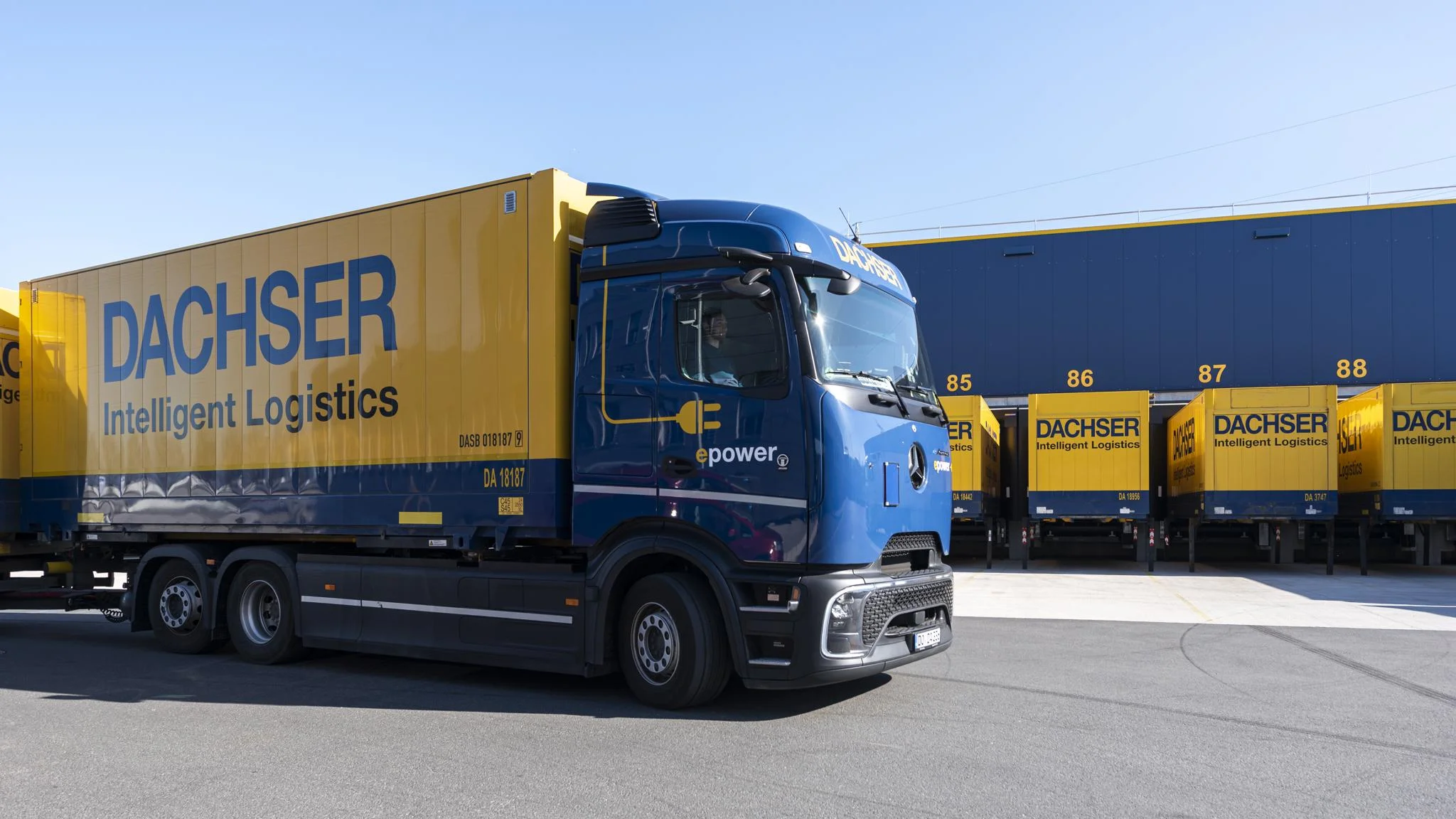 E-Lkw fährt auf DACHSER Betriesbsgelände mit Wechselbrücken im Hintergrund